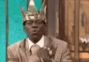 a man in a suit is wearing a crown on his head .