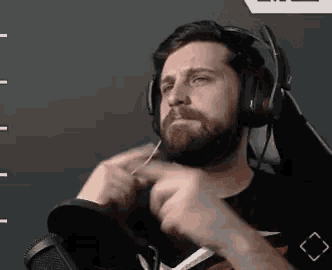 a man with a beard is wearing headphones and a microphone while sitting in front of a microphone .