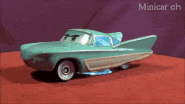 a toy car is sitting on a red surface with the words minicar ch written on the bottom