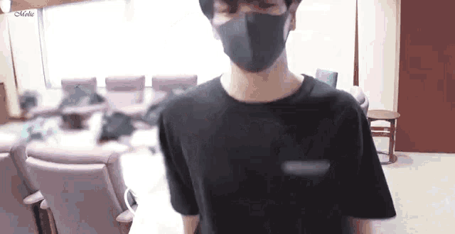 a man wearing a mask and a black shirt is standing in a room .
