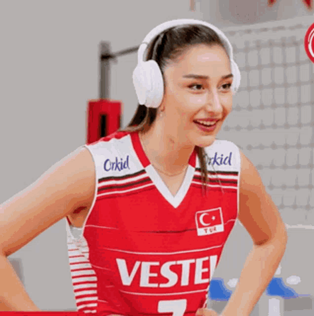 a woman wearing headphones and a red vest with vestel on it