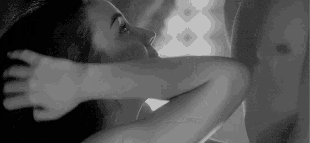 a black and white photo of a man and woman kissing .