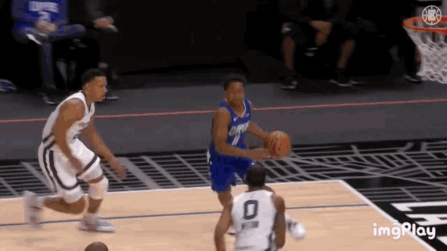 two basketball players are playing a game of basketball on a court . one of the players has the number 0 on his jersey .
