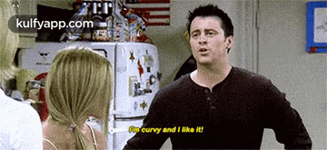 a man is talking to a woman in front of a refrigerator and says i 'm curvy and i like it .