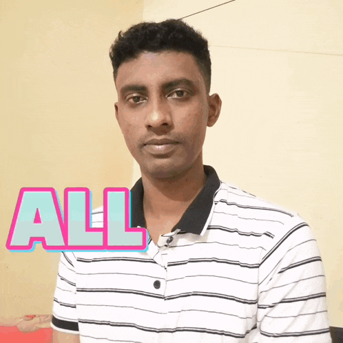 a man in a striped shirt is standing in front of a wall that says all