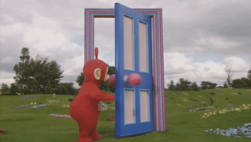 a red teddy bear is opening a blue door in a field
