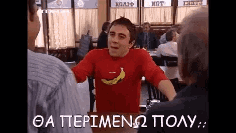 a man in a red shirt with a banana on it is talking to another man in a restaurant
