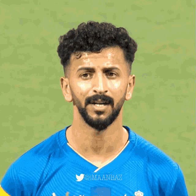 a man with a beard is wearing a blue shirt that says imaanbaz
