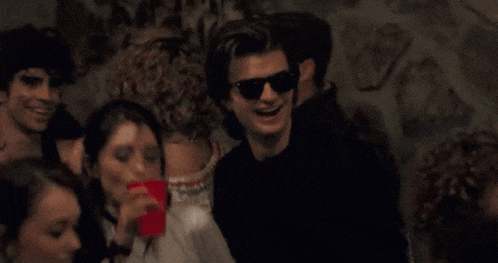 a man wearing sunglasses is dancing with a woman .