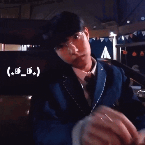 a man in a suit giving a peace sign in front of a sign that says ( x_b_x ) v