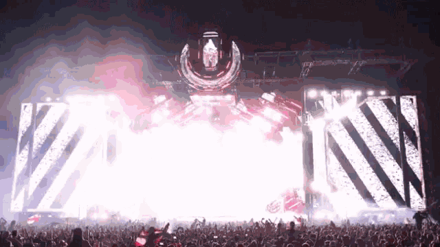 a crowd of people are standing in front of a stage at a concert watching a fireworks display .