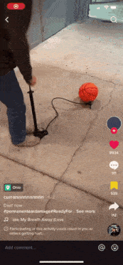 a person is pumping a basketball on a sidewalk with a tiktok app open