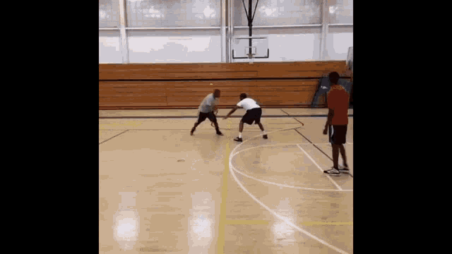 two men are playing basketball on a court in a gym .