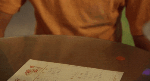 a person holding a plate with a piece of food on it and a receipt on the table