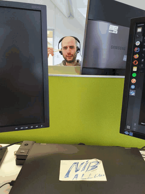 a man wearing a headset sits in front of a samsung computer monitor