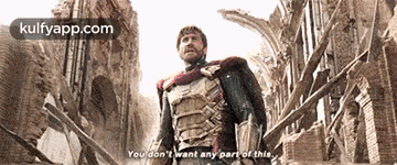 a man in a superhero costume is standing in front of a destroyed city .