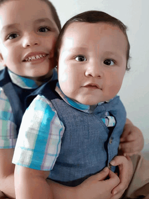 two young boys wearing plaid shirts and denim vests