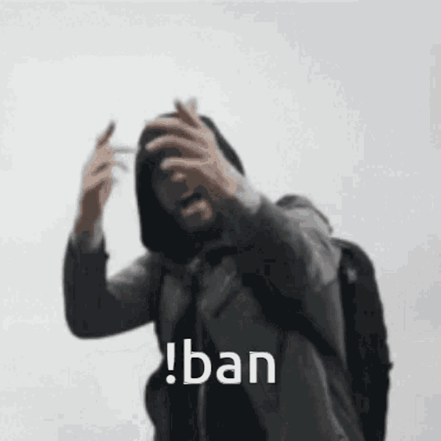 a man in a hooded jacket is holding his hands to his head and shouting the word ban .