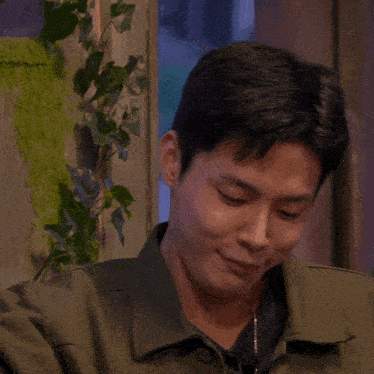 a close up of a man 's face with a plant behind him