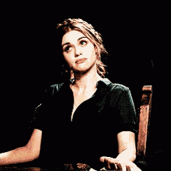 a woman is sitting in a chair with a man holding her hand .