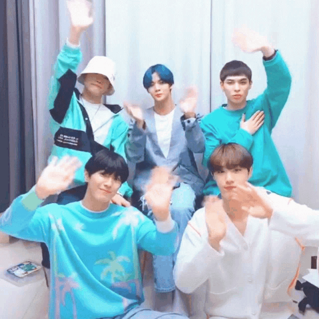a group of young men are posing for a picture and one of them is wearing a blue sweater with palm trees