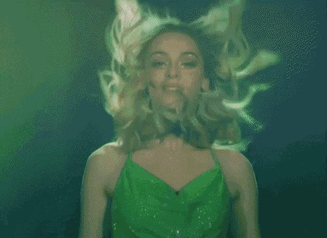 a woman in a green dress is standing in front of a green background .