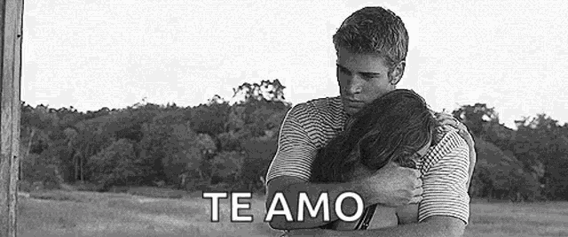 a man and a woman are hugging each other in a field and the man is saying `` te amo '' .