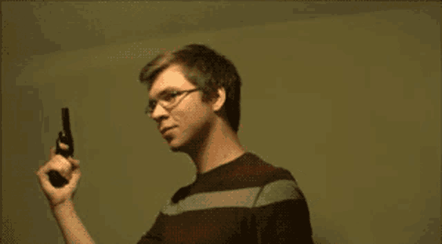 a man wearing glasses is holding a gun