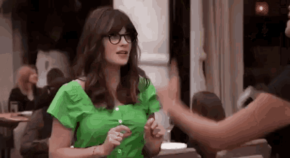 a woman in a green shirt and glasses is giving another woman a high five .