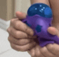 a close up of a person holding a purple and blue toy in their hands .