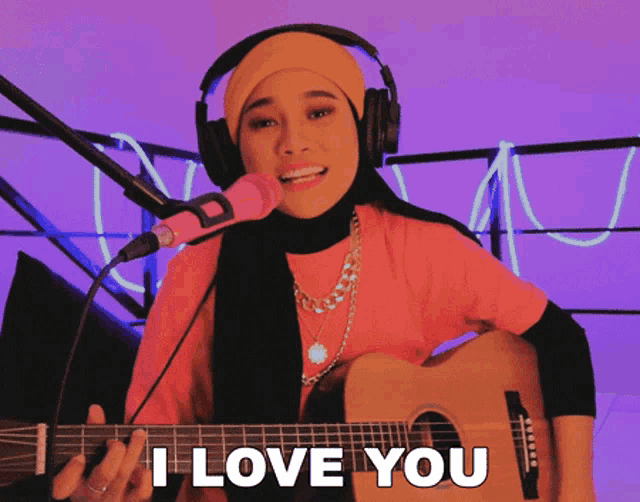 a woman singing into a microphone while holding a guitar that says " i love you " on it