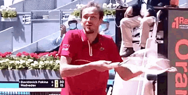 a man in a red shirt is holding a tennis racquet in his hand .