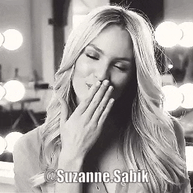 a black and white photo of a woman covering her mouth with her hands .
