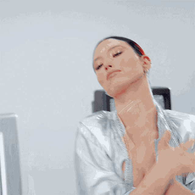 a woman is wearing a silver jacket and white top