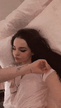 a woman laying on a bed with a tattoo on her arm