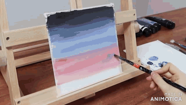 a person is painting on a canvas on an easel with the words made in animotica visible in the corner