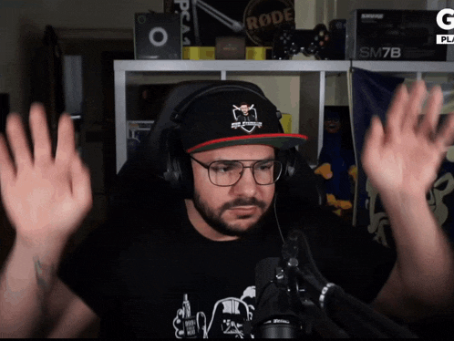 a man wearing headphones and a hat has his hands in the air in front of a rode sm7b