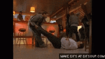 a man is laying on his back in a bar while another man stands behind him