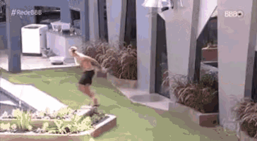 a man is jumping into a swimming pool while wearing shorts .