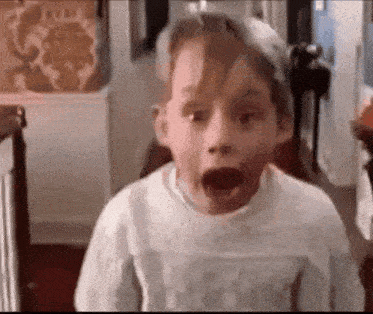 a young boy is making a surprised face in a room .