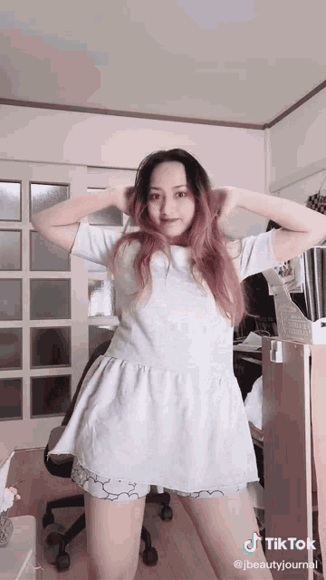 a woman with pink hair is standing in a room with a tiktok watermark