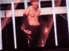 a shirtless man is standing on a stage in front of a screen .