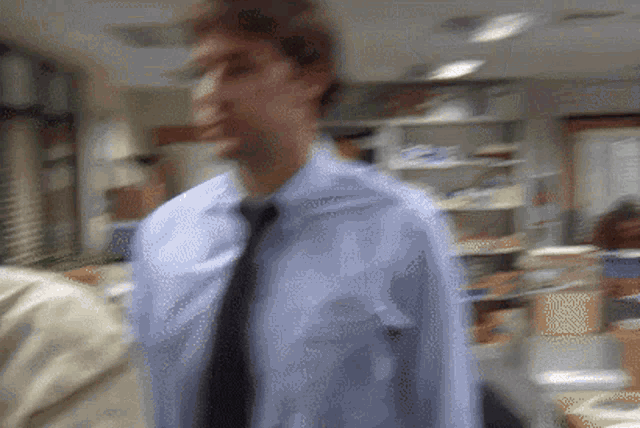 a blurry picture of a man in a blue shirt and tie in an office
