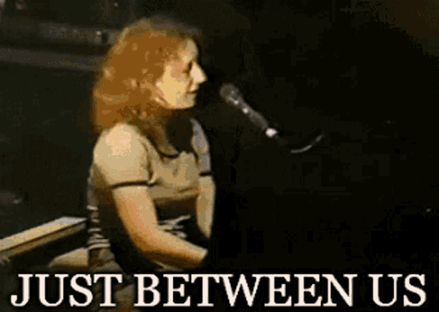 a woman is singing into a microphone and the words just between us are below her