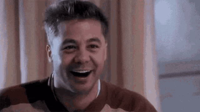 a man is laughing with his mouth open and his eyes closed .