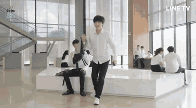 a man in a white shirt is walking in front of a group of people