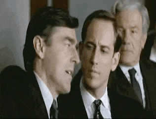 three men in suits and ties are standing next to each other in a room and talking .