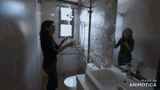 a woman is standing in a bathroom next to a sink and a toilet .