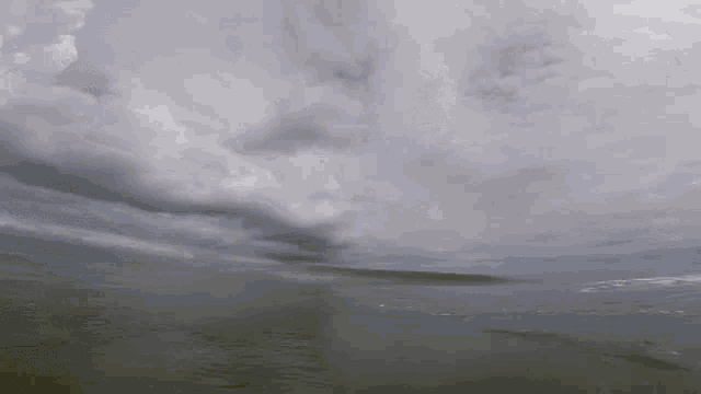 a cloudy sky over a body of water with waves coming in