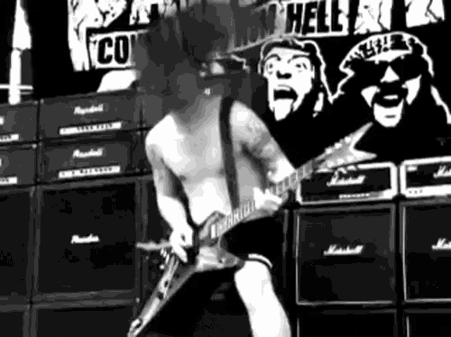 a man playing a guitar in front of a sign that says " hell "